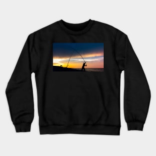 Fisherman cast fishing rods on the seashore at a dramatic sunset. Crewneck Sweatshirt